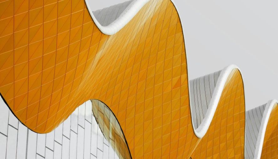 A rippling reflective building and roofline in silver and orange